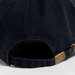 Rex Club | Close-up of the back of a dark blue baseball cap, showing an adjustable strap with a brass-colored metal buckle. The fabric appears textured, and stitching details are visible. | Custom Caps | Custom Hats | Team Headwear | UK