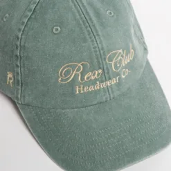 Rex Club | A faded green baseball cap with beige embroidered text that reads 