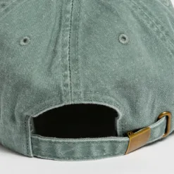 Rex Club | Close-up of the back of a faded green baseball cap, showing an adjustable strap with a metal buckle and stitched eyelets on the crown. | Custom Caps | Custom Hats | Team Headwear | UK
