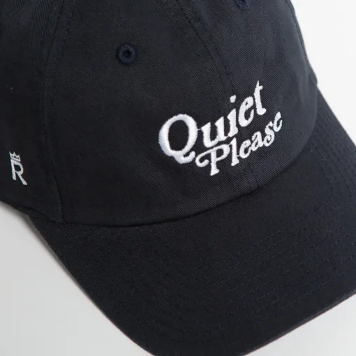 Rex Club | A close-up of the Golf: Quiet Please navy blue baseball cap, featuring "Quiet Please" embroidered in white on the front and a small white crown emblem visible on the side. | Custom Caps | Custom Hats | Team Headwear | UK