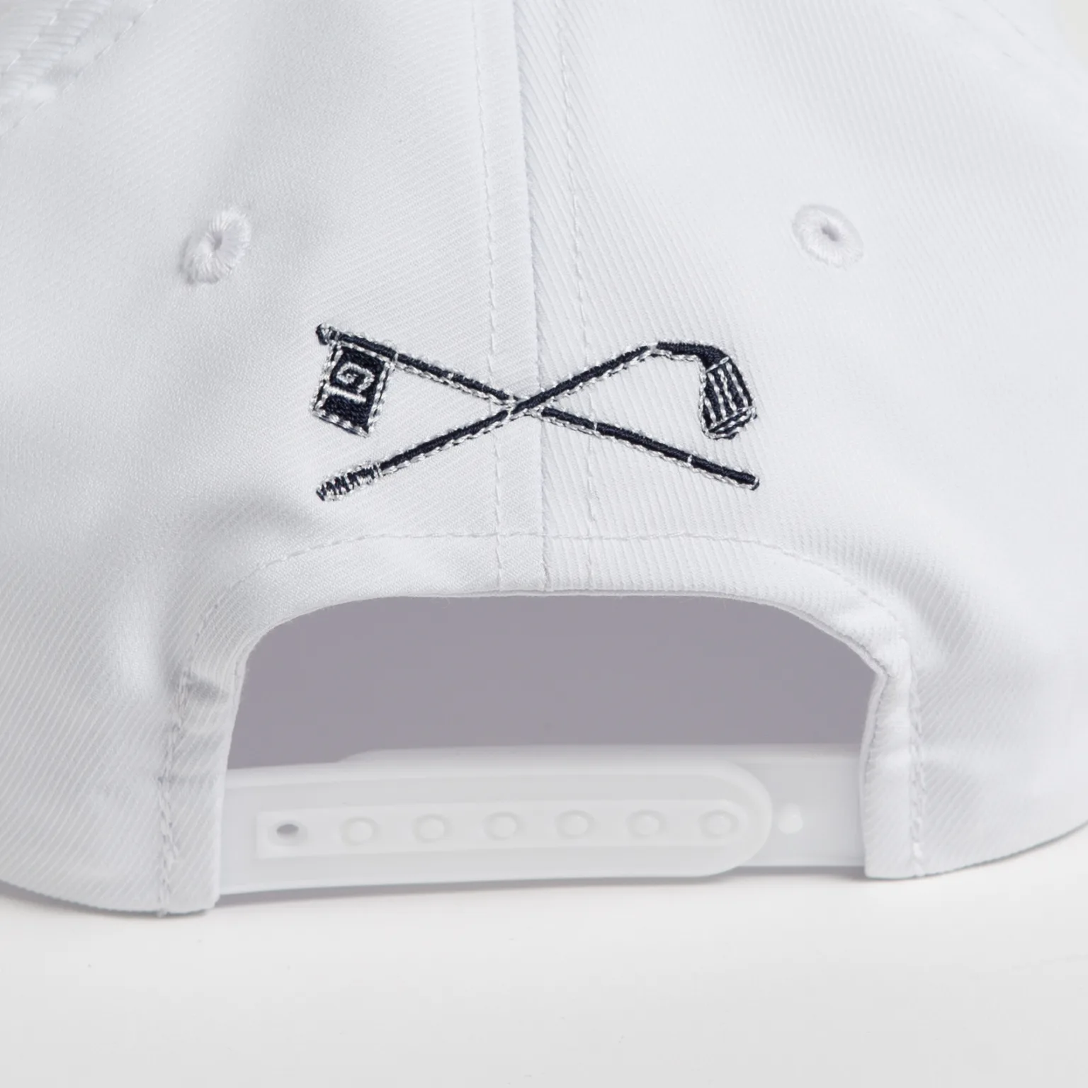 Rex Club | Close-up of the back of a Golf: Quiet Please white cap, showcasing an embroidered design of two crossed golf clubs and a checkered flag above the adjustable snapback strap. | Custom Caps | Custom Hats | Team Headwear | UK