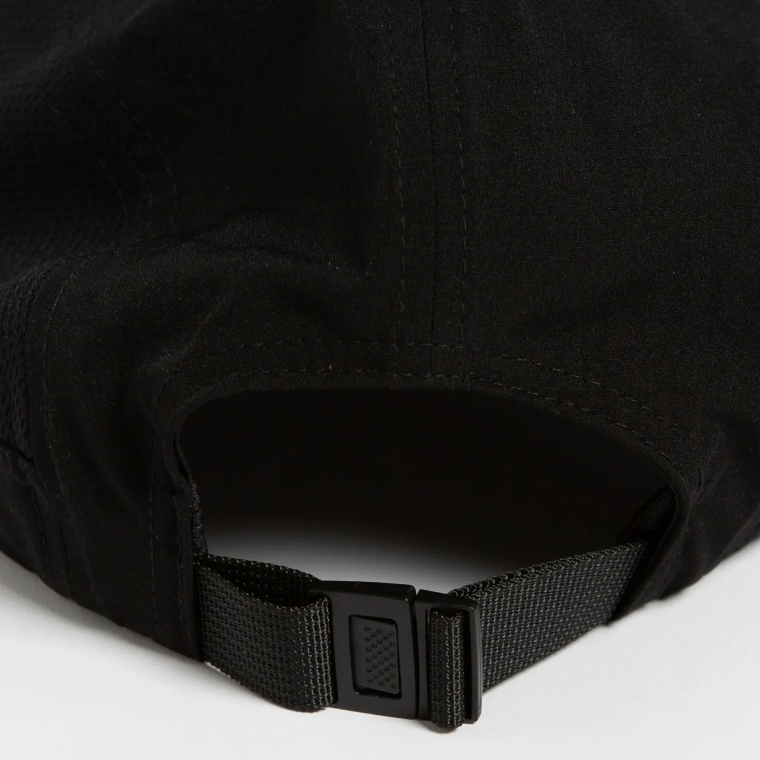 Rex Club | Close-up of the back of a Running Caps black cap, featuring an adjustable strap with a plastic clip buckle. The cap's fabric has visible stitching and a slightly textured look, shown resting on a flat surface. | Custom Caps | Custom Hats | Team Headwear | UK