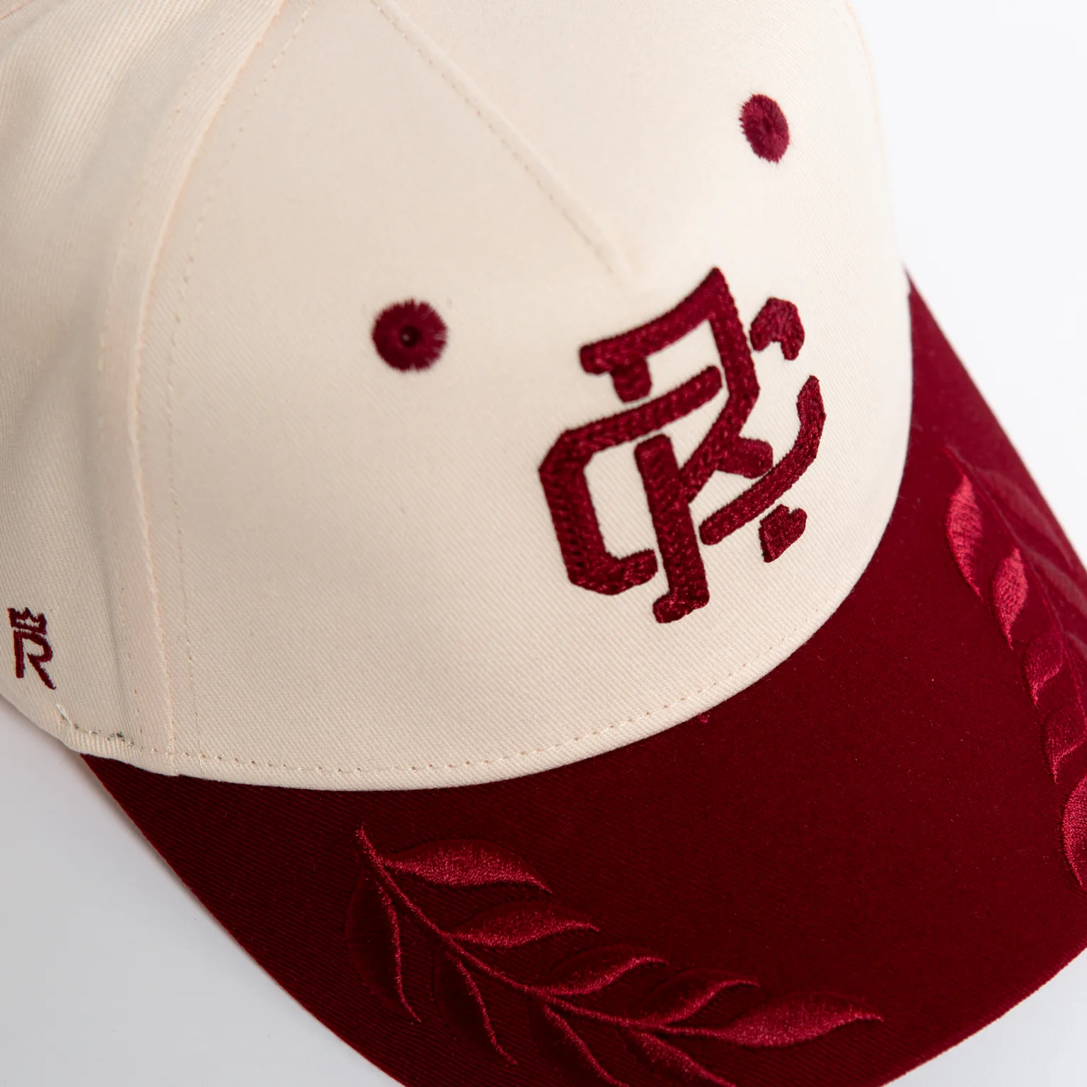 Rex Club | The Rex Club - TwoTone - Canvas Cap is a beige and maroon baseball cap with burgundy embroidered stylized letters on the front, leaf designs on the brim, and small side embroidery. | Custom Caps | Custom Hats | Team Headwear | UK