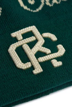 Rex Club | Close-up of cream-colored embroidered “R” and “C” letters on dark green Rex Club Script and Monogram Beanie. | Custom Caps | Custom Hats | Team Headwear | UK
