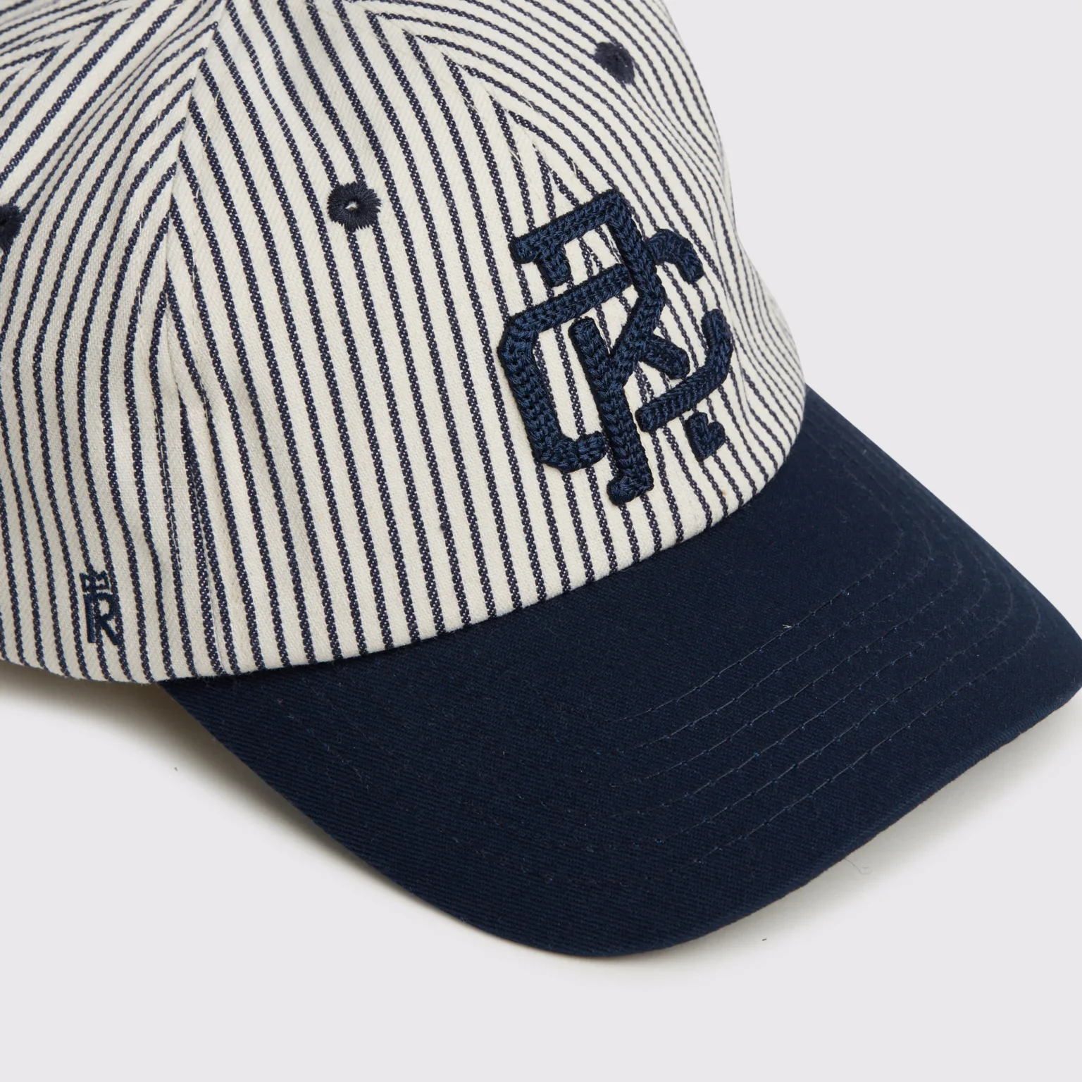 Rex Club | The RC - Baseball Pin - SS26 Navy features a white crown with thin navy vertical stripes, a navy brim and eyelets, and a dark blue embroidered monogram logo on the front. | Custom Caps | Custom Hats | Team Headwear | UK