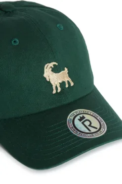 Rex Club | The Goat is a dark green baseball cap with an embroidered beige goat on the front and a round brim sticker reading 