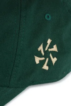 Rex Club | Close-up of the Goat cap in dark green fabric, featuring a small cream-coloured circular arrow embroidery. | Custom Caps | Custom Hats | Team Headwear | UK