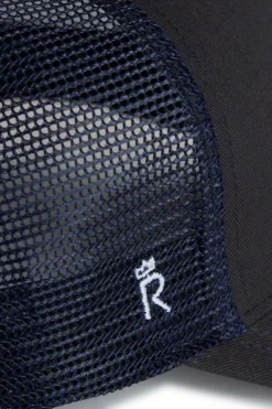 Close-up of a navy mesh hat with a hexagonal grid pattern and white embroidery revealed at the edge.