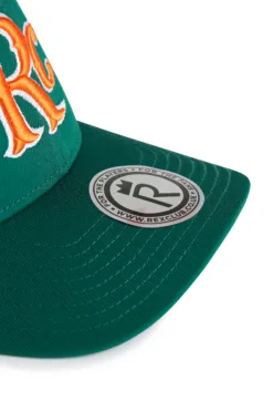 Rex Club | Close-up of the RC 26 Performance green baseball cap with orange embroidery and a round silver sticker on the brim featuring the Rex Club logo and website. | Custom Caps | Custom Hats | Team Headwear | UK