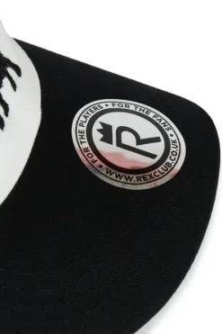 Rex Club | Close-up of the OFFSEASON 26 Trucker cap in black and white, featuring a round brim sticker with a crown logo, the letter 