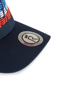 Rex Club | Close-up of the OFFSEASON 26 cap’s navy blue peak with a round metallic “R” sticker, a crown, and www.rexclub.com. The cap has a red, white, and blue stitched pattern on the crown. | Custom Caps | Custom Hats | Team Headwear | UK