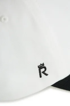 Rex Club | Close-up of the Goat cap: features white fabric, a small black embroidered “R” with a crown near the black peak. | Custom Caps | Custom Hats | Team Headwear | UK