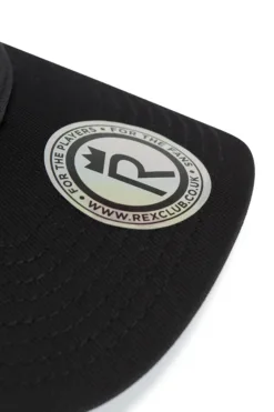 Close-up of a black cap brim with a circular white logo sticker on it.
