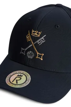 St Peter's York Navy cap with gold crown embroidery and white thread detailing on the front panel, plus a round holographic sticker on the brim.